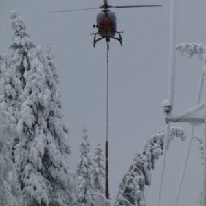A helicopter is a great help in detecting, preventing and repairing the damage caused to power lines by snow load. It may take a long time to find a tree that has bent across or fallen down on a power line deep in the forest, unless you use a helicopter. They are also used to map areas with risk of snow load, and information on this can be sent to the maps of repair teams via the mobile network. The photo shows snow being dropped with the help of a helicopter pulling a short log attached to a wire rope along the edge of the power line corridor. The log hits the trees bent across the corridor and causes the snow to fall off. For the pilot, this is an extremely demanding task, as the log must be prevented from touching the power lines at all times. Photo: Elenia
