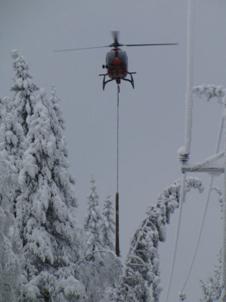 A helicopter is a great help in detecting, preventing and repairing the damage caused to power lines by snow load. It may take a long time to find a tree that has bent across or fallen down on a power line deep in the forest, unless you use a helicopter. They are also used to map areas with risk of snow load, and information on this can be sent to the maps of repair teams via the mobile network. The photo shows snow being dropped with the help of a helicopter pulling a short log attached to a wire rope along the edge of the power line corridor. The log hits the trees bent across the corridor and causes the snow to fall off. For the pilot, this is an extremely demanding task, as the log must be prevented from touching the power lines at all times. Photo: Elenia
