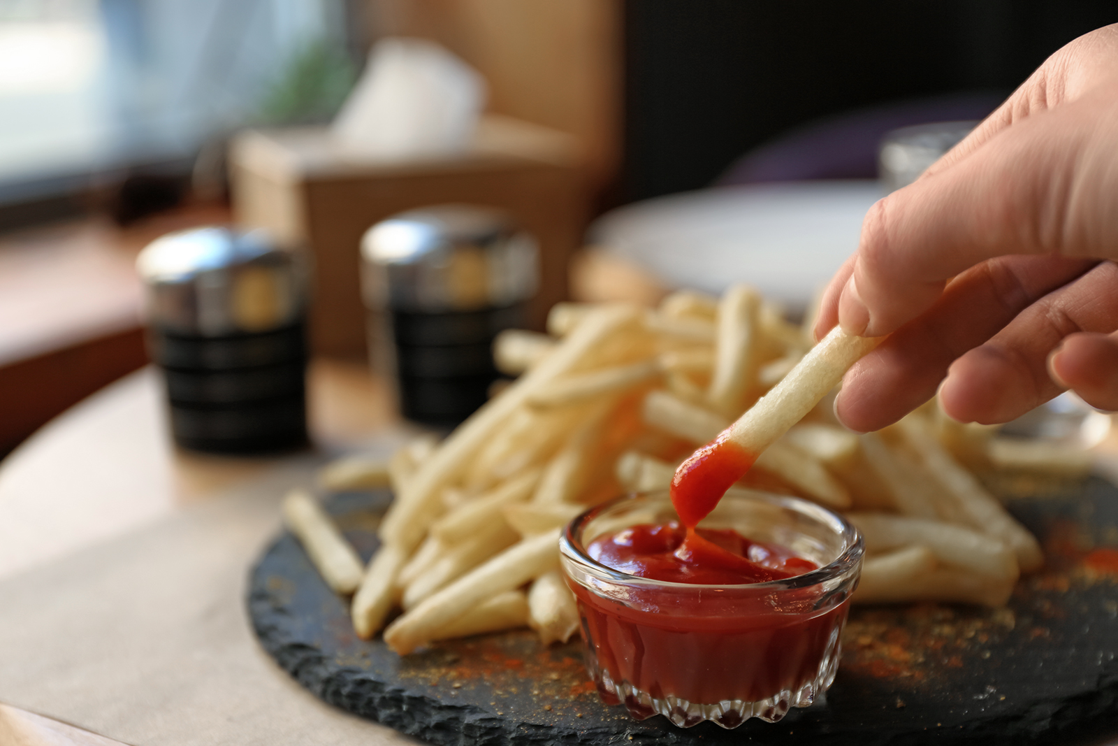 Dipping french fries into the ketchup. Photo: Shutterstock