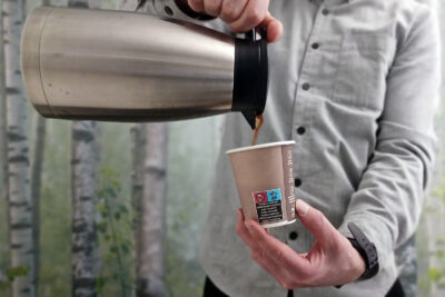 A man is pouring coffee into a cup with a turtle logo.