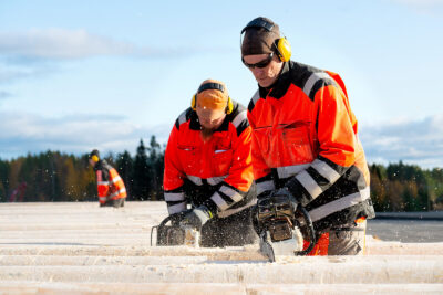 Two men sawing utility poles. Photo: Scanpole Oy